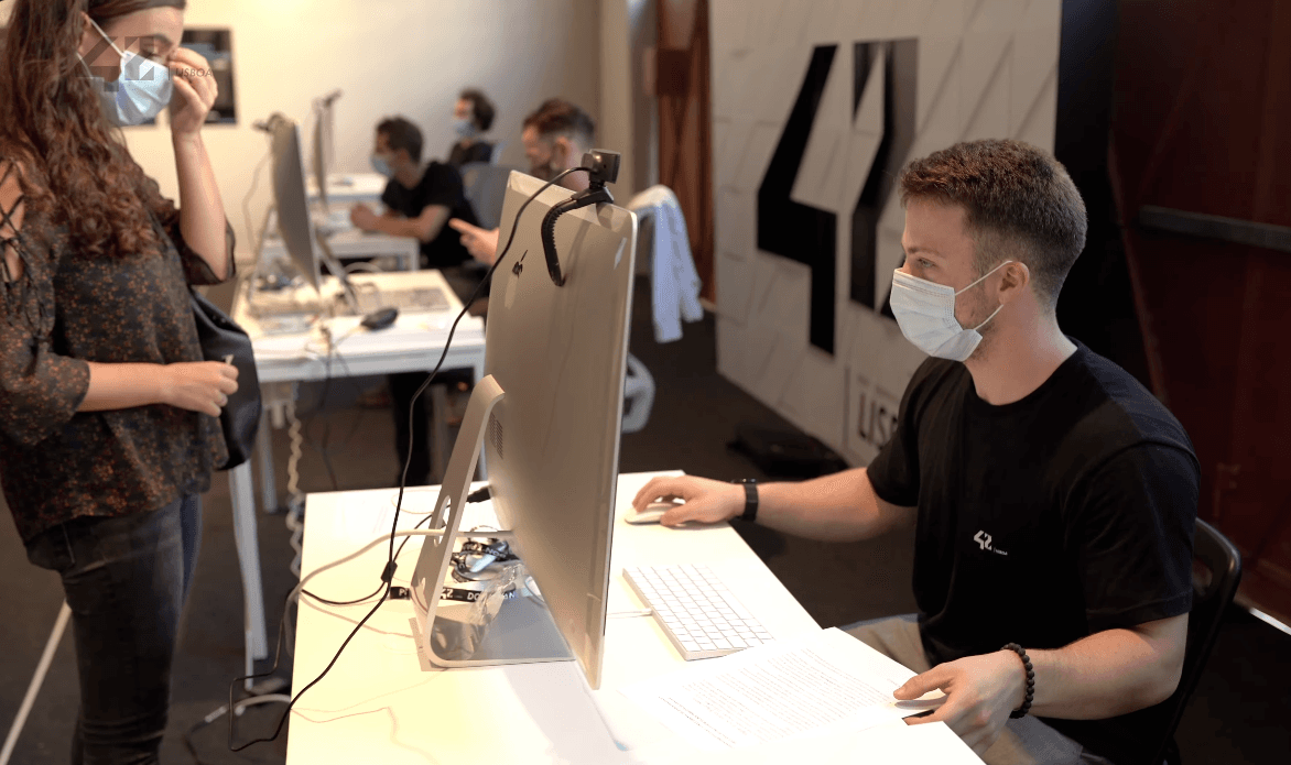 Julien Lange encadrant une piscine à la 42 Lisboa — étudiants sur iMacs dans l'open space